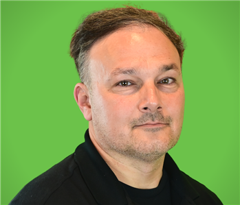 A male SERVPRO employee smiles in front of a green background.