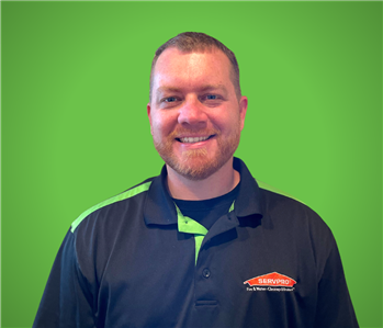 Male SERVPRO Employee smiling in front of a beige wall.