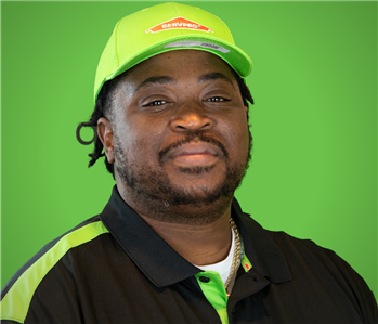 Male SERVPRO Employee smiling in front of a beige wall.