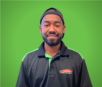 Male SERVPRO Employee smiling in front of a beige wall.