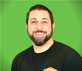 Male SERVPRO Employee smiling in front of a beige wall.